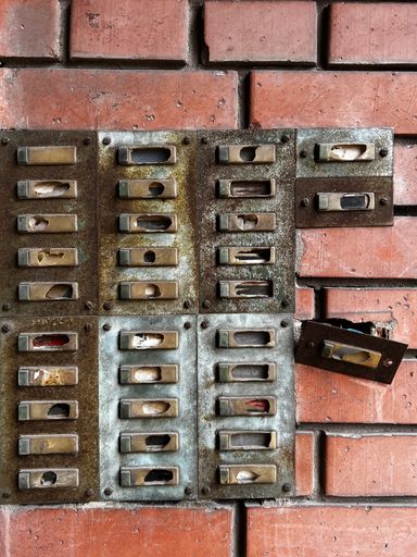 A vertical shot of an old damaged building intercom on a brick wall background