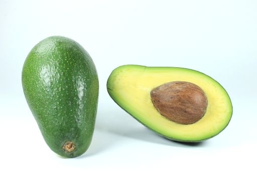A closeup shot of the avocado fruit cut in half on the white background
