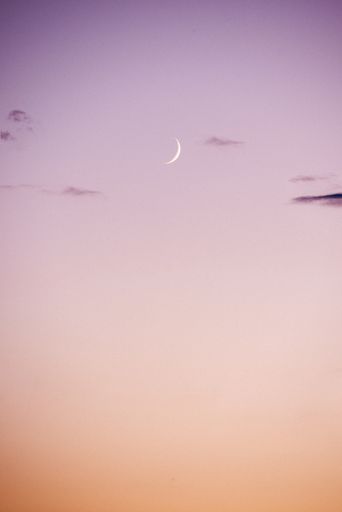 A vertical shot of the crescent moon in the pink-purple sky