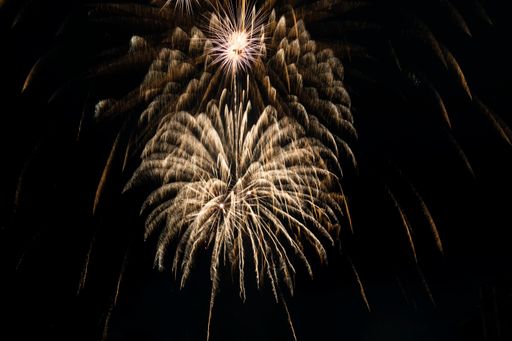 Bright fiery rays from exploding pyrotechnics against the black background of the night sky. Background with festive fireworks.