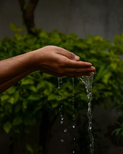 A vertical closeup of the water dripping from the man's hands.