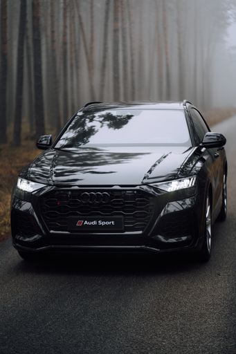 A vertical shot of a silver Audi RS 6 on the road in a foggy forest