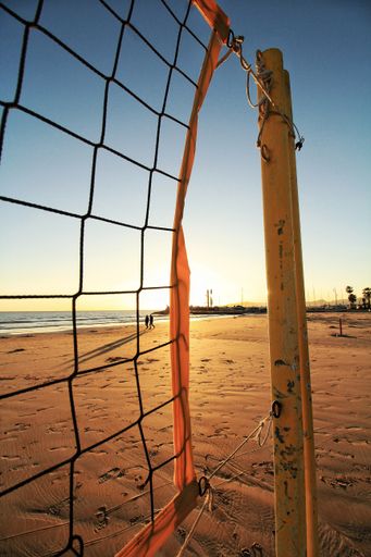 A net of volleyball on the beach and the sunset seen in the blurred background