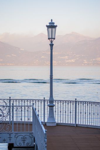 A vertical closeup shot of the lamp with the sea and the mountains on the background in Stresa, Italy