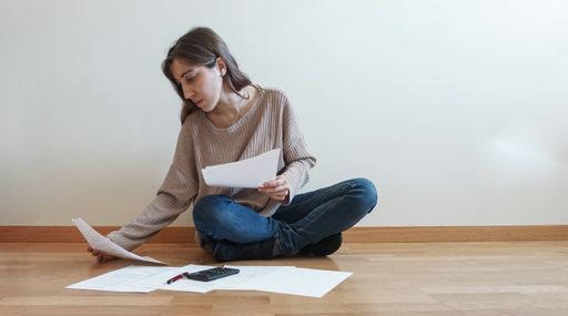 A closeup shot of a worried young  Caucasian female reviewing documents and checking invoices at home