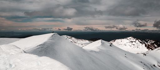 A wide shot of mountains covered in snow under a cloudy sky