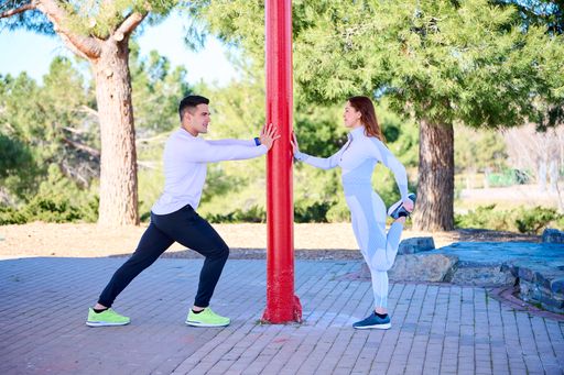 A young man and woman exercising at the outdoor gym
