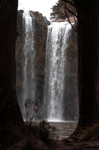 A vertical selective shot of a waterfall flowing down a cliff