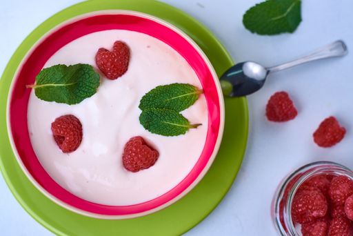 A top view of yogurt cream with raspberries in a bowl