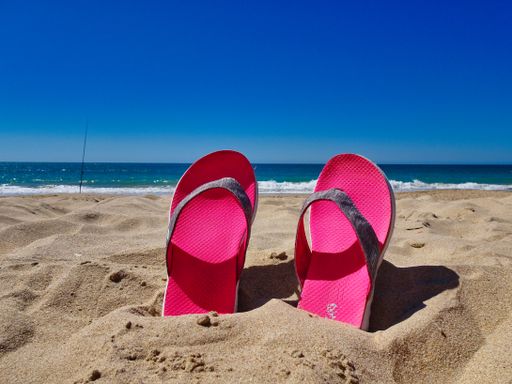 A pair of pink slippers in a sand