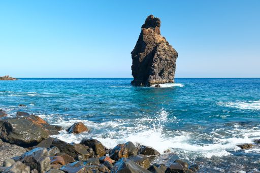Volcanic coast and rock formation Roque de la Bonanza surrounded by blue Ocean on the island El Hierro. Huge Rock sticking out of the water.