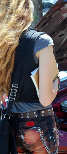 A vertical shot of a blonde girl wearing a fancy outfit and holding her notebooks