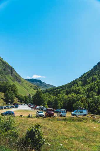 A vertical shot of vans parked near a waterfall in the Pyrenees