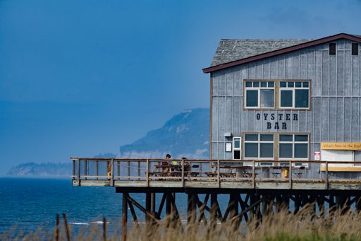 A Beautiful shot of a restaurant with the Pacific Ocean and mountains in the background in Homer, USA