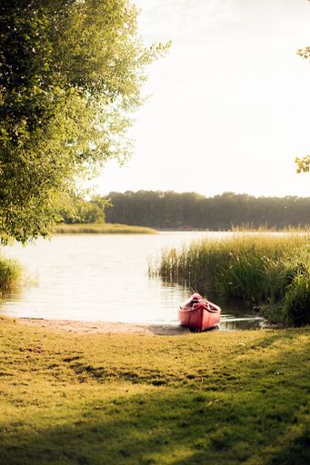 A red fishing boat at the coast of a lake