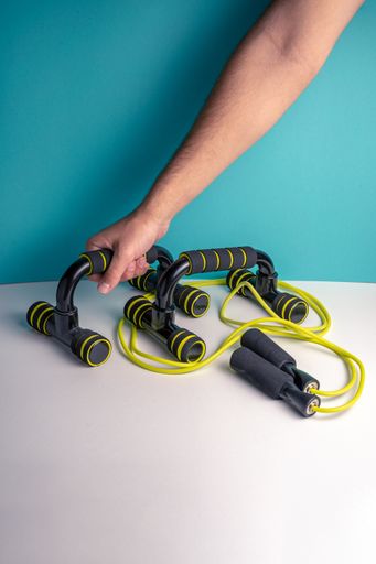 A vertical shot of a person putting push up bars on the table near a jump rope - fitness concept