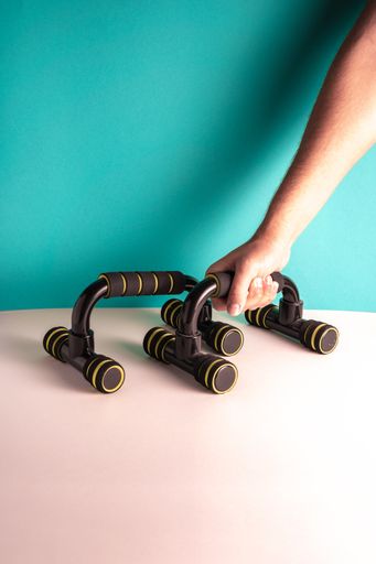 A vertical shot of a person putting push up bars on the table against a blue wall - fitness concept