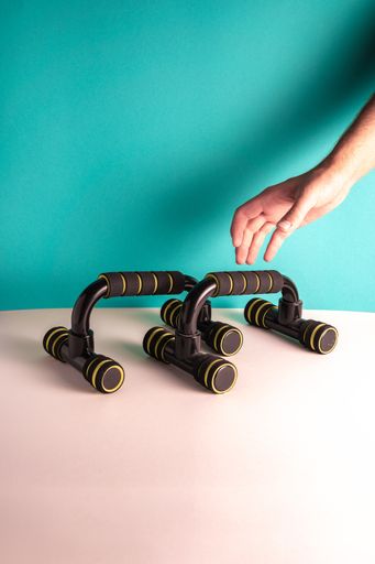 A vertical shot of a person putting push up bars on the table against a blue wall - fitness concept