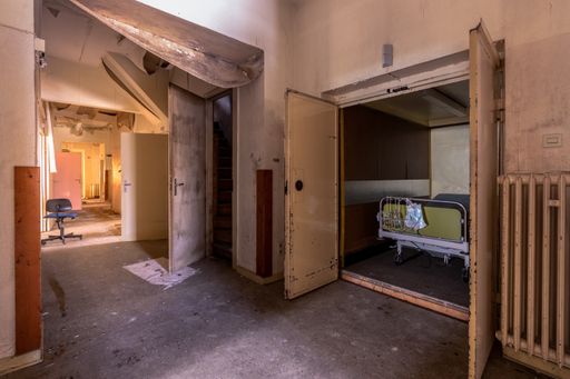 A hallway in an old abandoned hospital, a hospital bed is in the elevator.