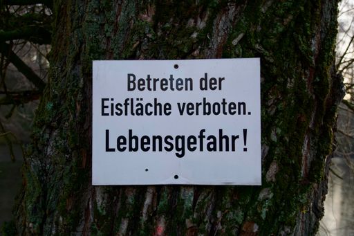 A sign nailed to a tree with the German inscription entering the ice surface prohibited danger to life
