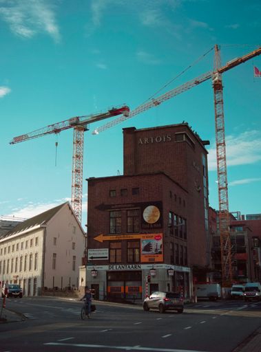 A building being renovated with yellow cranes in the back in Mechelen, Belgium