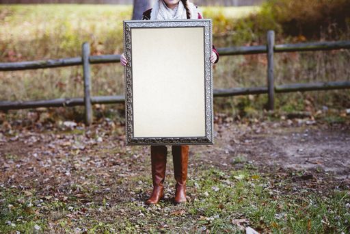 A selective shot of a person holding a blank picture frame as a space for your text