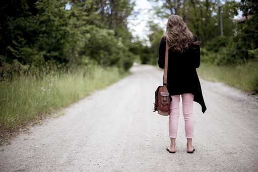 A female standing on an empty road with a blurred background shot from behind