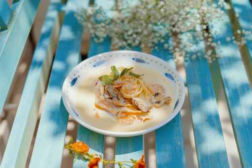 A bowl of creamy soup with noodles and mushrooms on the table under the sunlight - perfect for food concepts