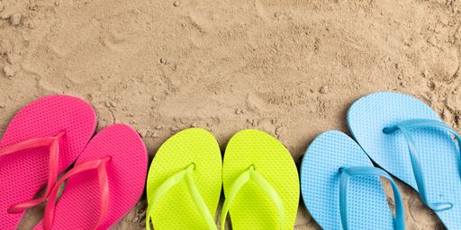 A top view of colorful flip flops in sand, summer and vacation concept