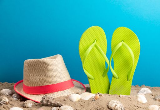 A closeup of a strand hat with flipflop and shellfish blue background, summer time