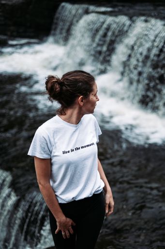 Young oman looking at the waterfall, live in the moment quote, Aysgarth Falls, England, UK
