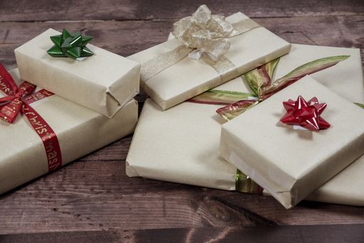 A selective closeup shot of decorated gift boxes wrapped in beige wrapping papers on a wooden surface