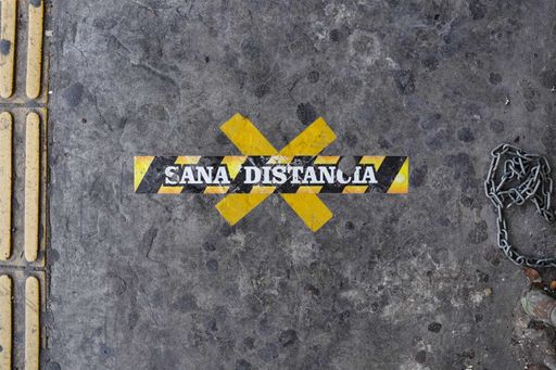 A closeup shot of black and yellow tapes on the wall with [SANA DISTANCIA - HEALTHY DISTANCE] printed on it - COVID-19