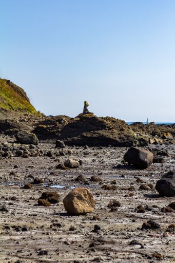 A vertical shot of a rocky seashore under a blue sky