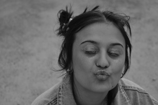 A grayscale shot of a young lady of mixed ethnicity posing with makeup on doing duckface
