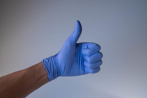 A hand in medical glove thumb up on blue background-  Covid-19
