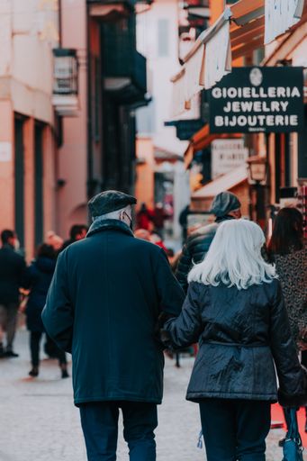A rear view of an elderly couple walking along streets in Stresa, Italy