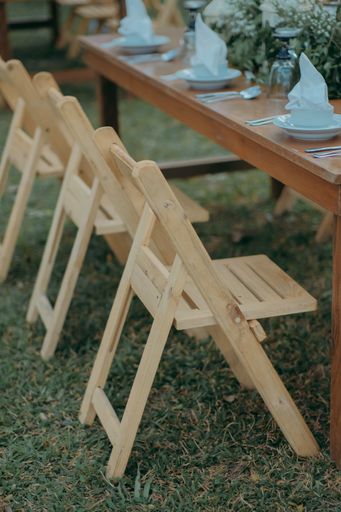 A vertical closeup shot of the wooden chairs and decorated table for the event