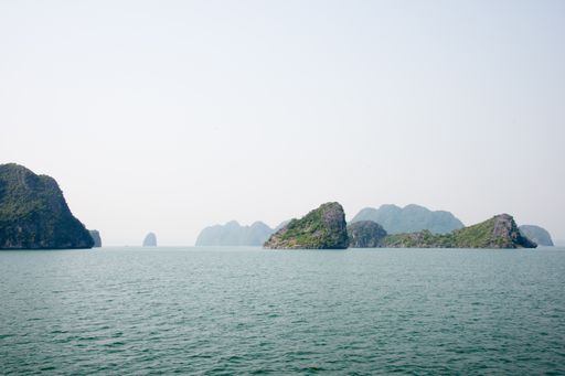 A scenic view of the emerald water and cliffs covered in green forests of the Ha Long Bay, Vietnam