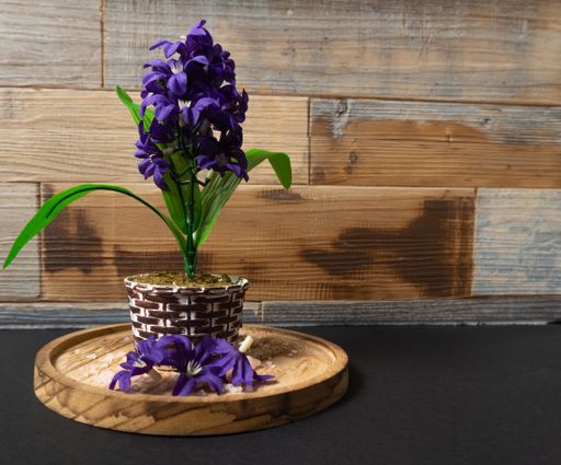 A closeup of an artificial potted Hyacinth on a wooden surface on the table
