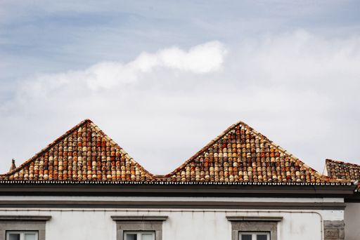 An outdoor view of old colored tile roof of a house under a wispy sky