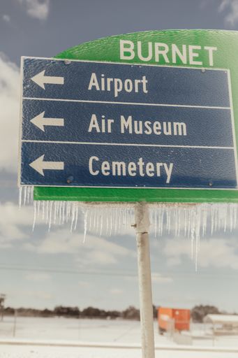 A vertical shot of some signs with icicles hanging from the them