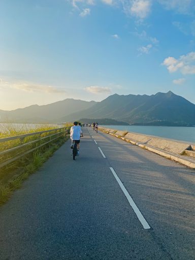 A vertical back view of bicyclists on the road in Tai Mei Tuk, Hong Kong, China