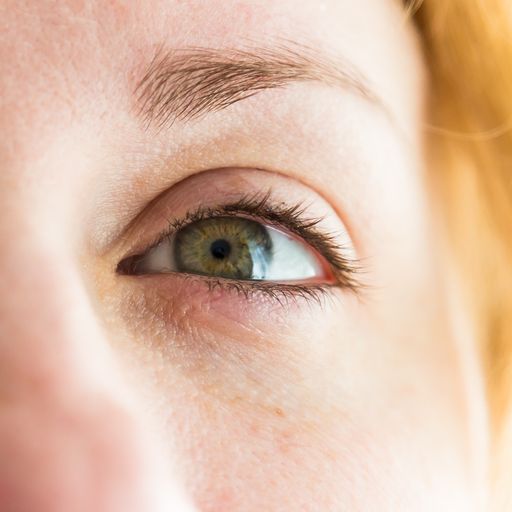 A closeup of a green eye of a blonde caucasian woman