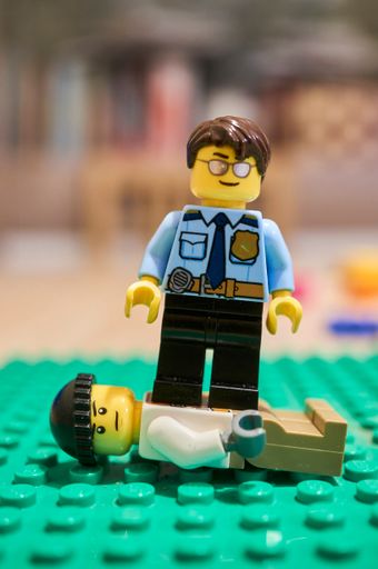 A Lego brand policeman toy figurine standing on a prisoner