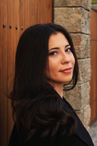 An attractive Romanian woman in dark casual dress leaning on a wooden surface in Lasi, Romania