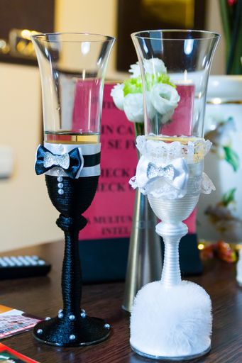 A vertical shot of the beautifully decorated bride and groom glasses