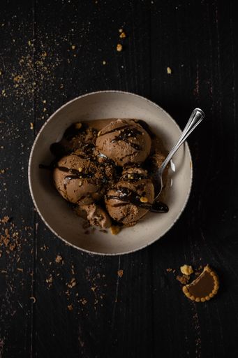A top view of chocolate ice cream with glaze in a white bowl