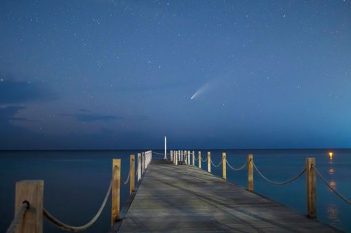 A landscape view of a pier on the beach and starry sky