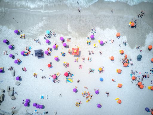 The Umbrellas and bathers on the beautiful white sand at the beach